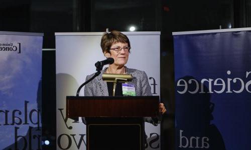 A woman speaking in front a sign that says science